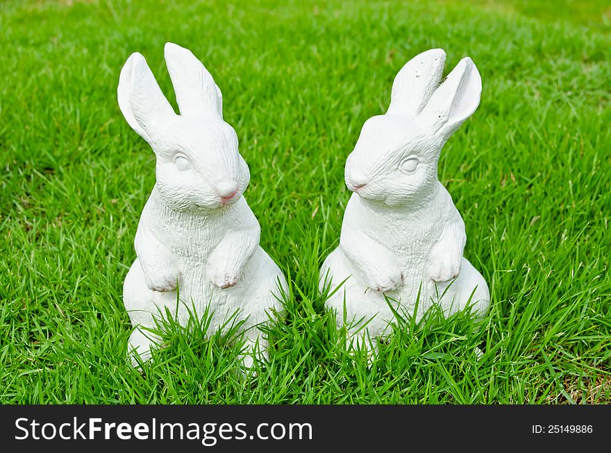 Couple of white cement rabbit on green grass. Couple of white cement rabbit on green grass