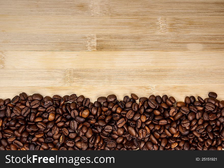 A pile of coffee beans forming a simple stripe frame on a natural background. A pile of coffee beans forming a simple stripe frame on a natural background.