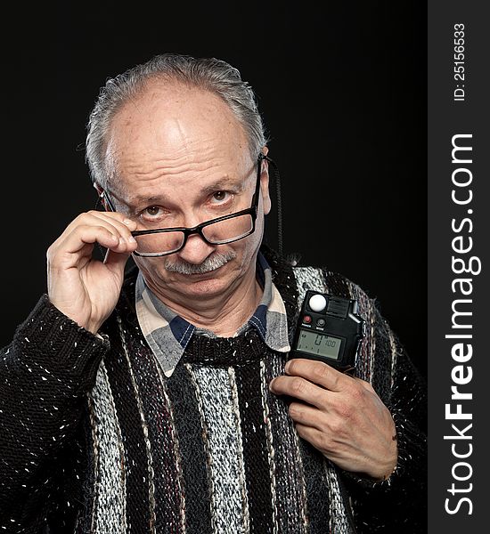 Portrait of a senior photographer with a flash meter and glasses