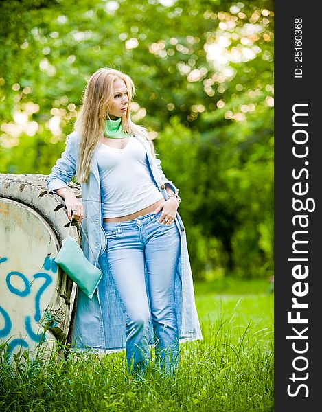 Attractive girl posing in jeans and blue coat outdoor in summer. Attractive girl posing in jeans and blue coat outdoor in summer