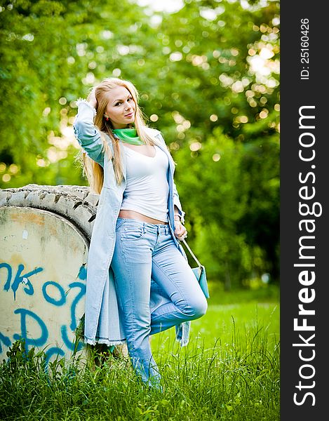 Attractive girl posing in jeans and blue coat outdoor in summer. Attractive girl posing in jeans and blue coat outdoor in summer