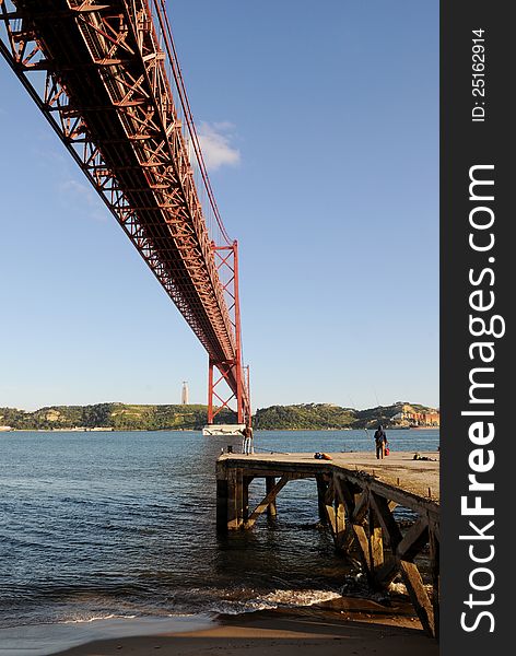 Fishing pier under the 25 de Abril Bridge (or 25th April Bridge), Lisbon, Portugal.