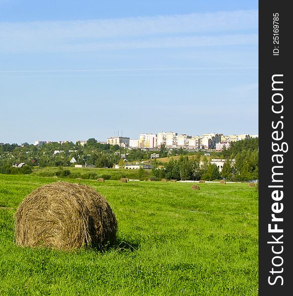 Summer haymaking. A haystack against a city.