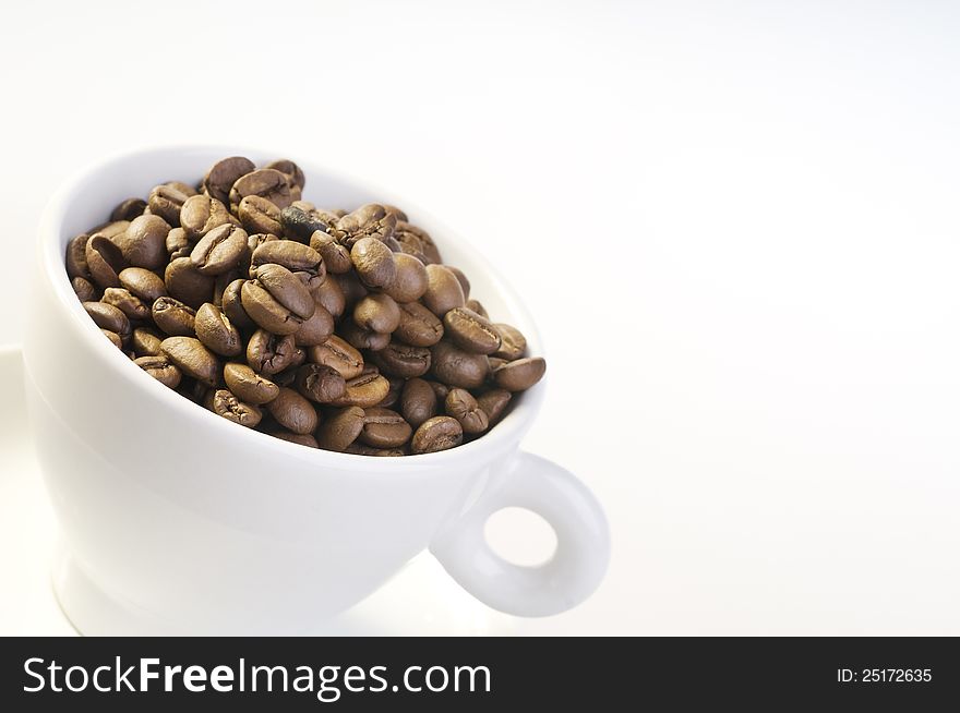 Coffee beans in a cup isolated over white background. Coffee beans in a cup isolated over white background