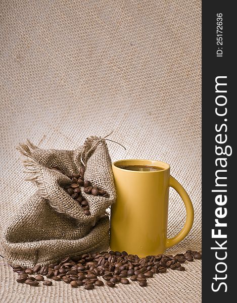 Cup of coffee with beans and sack over brown burlap background. Cup of coffee with beans and sack over brown burlap background