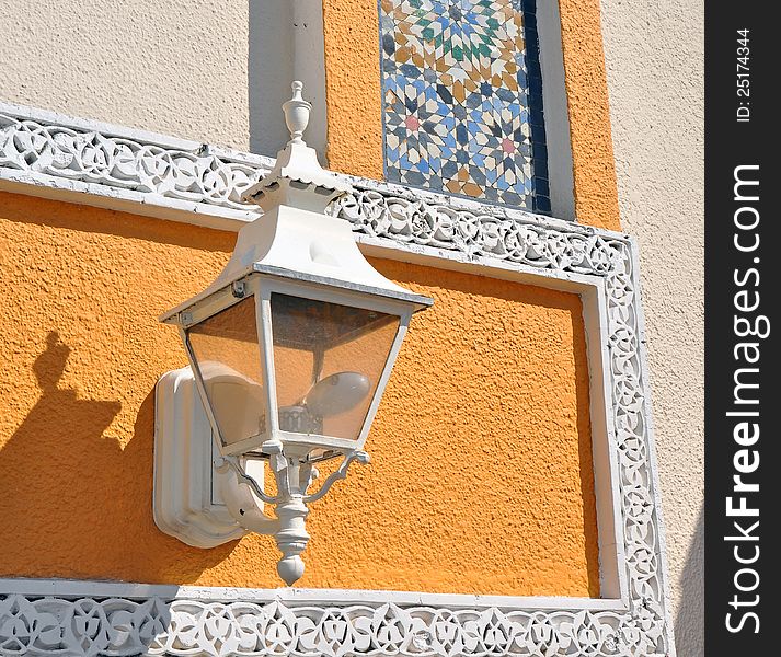 White street lamp with a very colorful north African traditional wall behind it. White street lamp with a very colorful north African traditional wall behind it