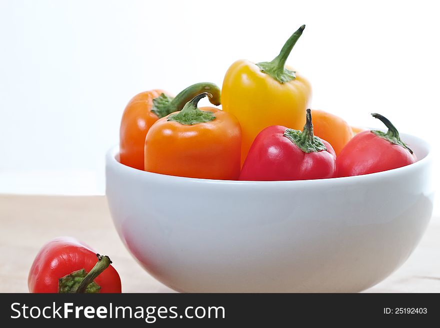 White bowl containing brightly colored mini sweet peppers. White bowl containing brightly colored mini sweet peppers