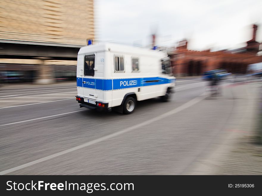 Police van driving on a city street. The picture was taken at the Oberbaum Bridge in Berlin with long exposure and by panning the camera, so the environment is shown in motion blur. Police van driving on a city street. The picture was taken at the Oberbaum Bridge in Berlin with long exposure and by panning the camera, so the environment is shown in motion blur