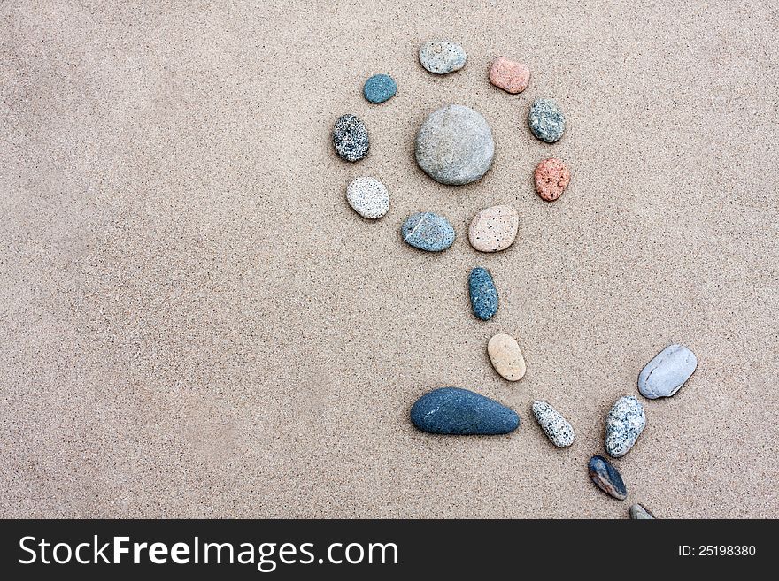 Pebbles were laid out on the sand in form of a flower. Pebbles were laid out on the sand in form of a flower