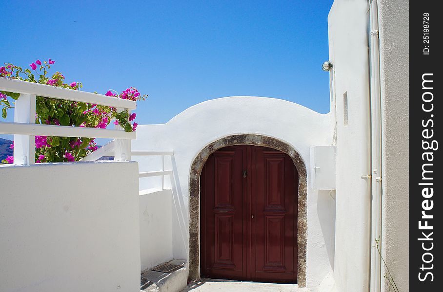 Santorini terrace with pink beautiful flowers and small doors