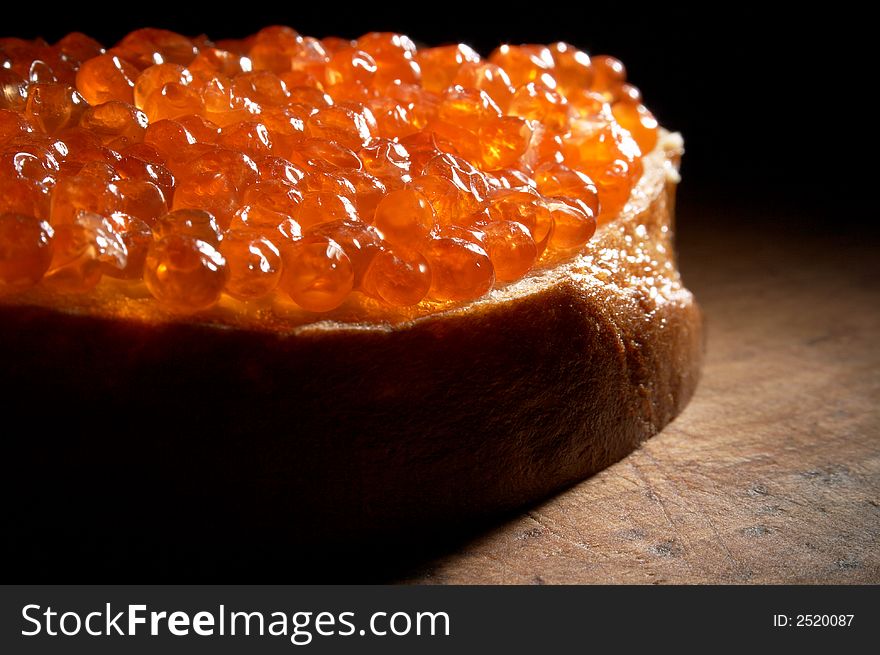 Sandwich with red caviar on a wooden table