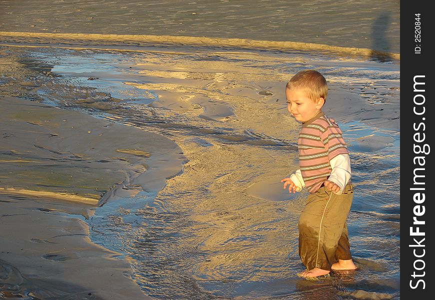 Young boy running in a stream on the beach. Young boy running in a stream on the beach