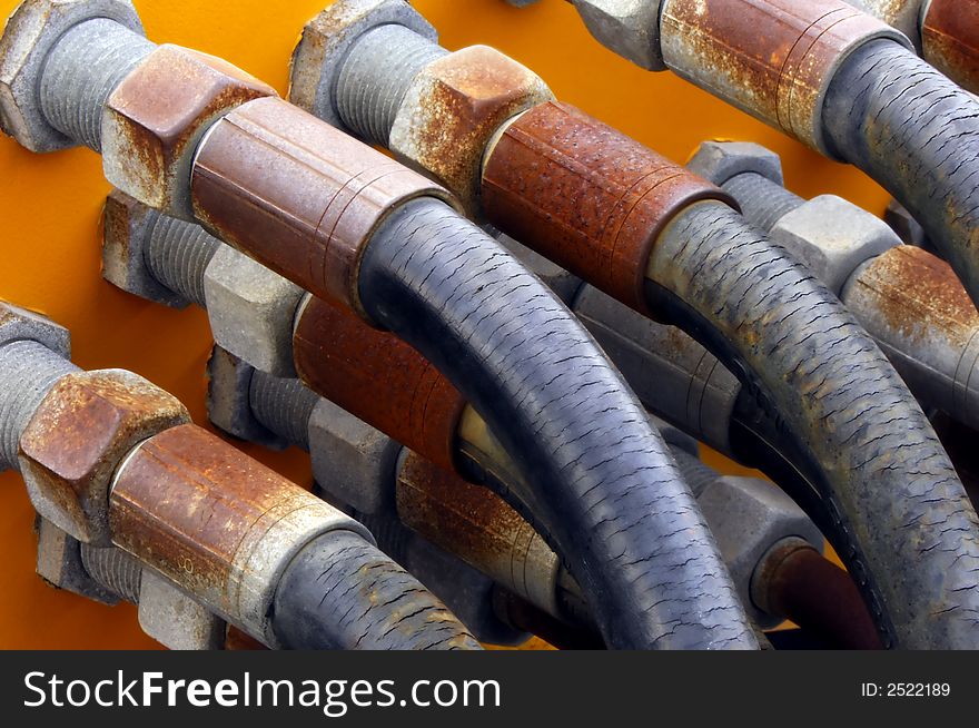 Image shows a set of old and weathered tubes connected to a metallic surface. Image shows a set of old and weathered tubes connected to a metallic surface