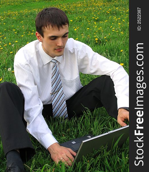 Businessman with laptop sitting on the grass