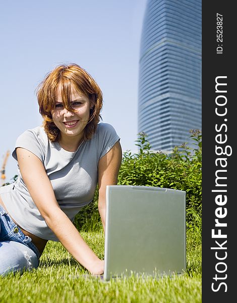 Young girl with laptop on the grass before office building. Young girl with laptop on the grass before office building