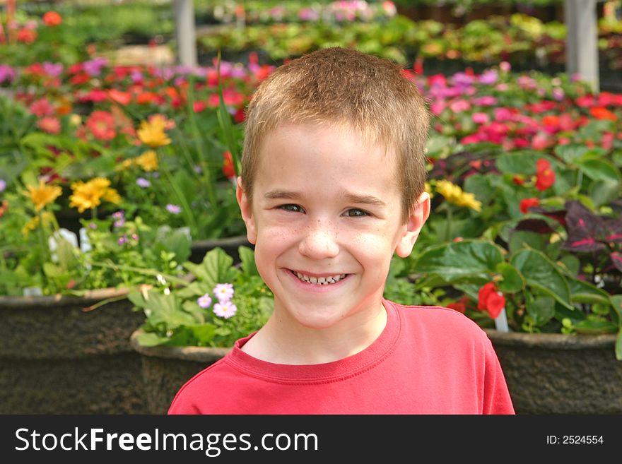 Young Boy Smiling in Front of Flowers