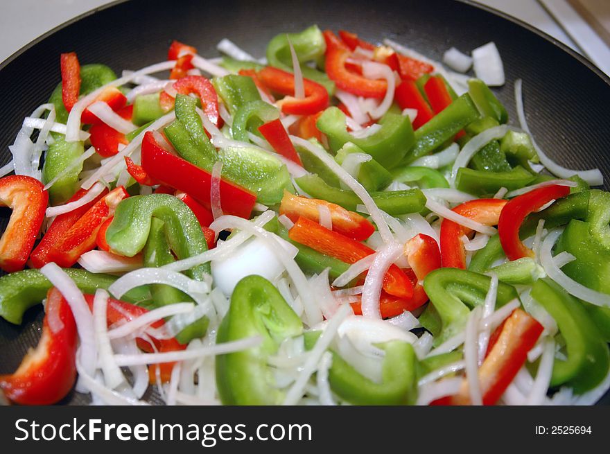 Close-up shot of red and green peppers and onions stir-frying in a skillet.  Shallow depth of field. Close-up shot of red and green peppers and onions stir-frying in a skillet.  Shallow depth of field.