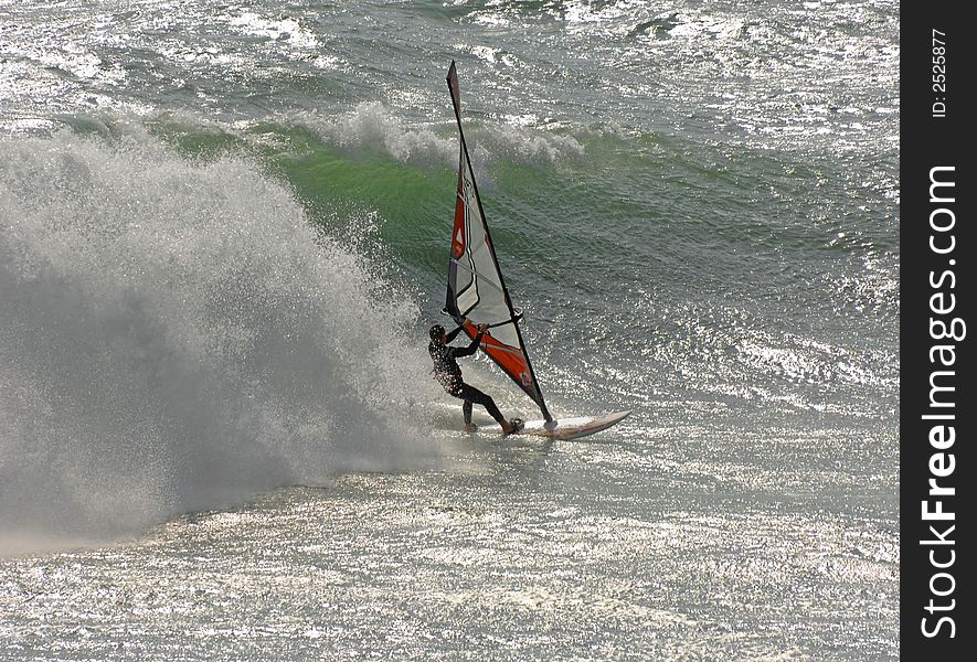 Fast moving windsurfer surfing over large waves