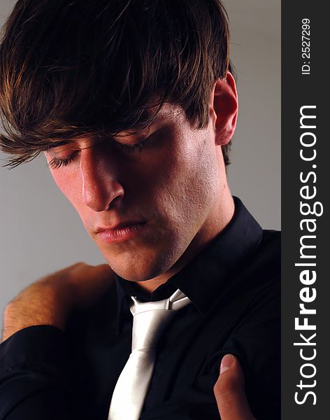 Portrait of a young man with a black shirt and a white tie in a thoughtful pose. Portrait of a young man with a black shirt and a white tie in a thoughtful pose.