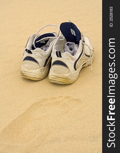 Dirty shoes with socks left on a sandy beach