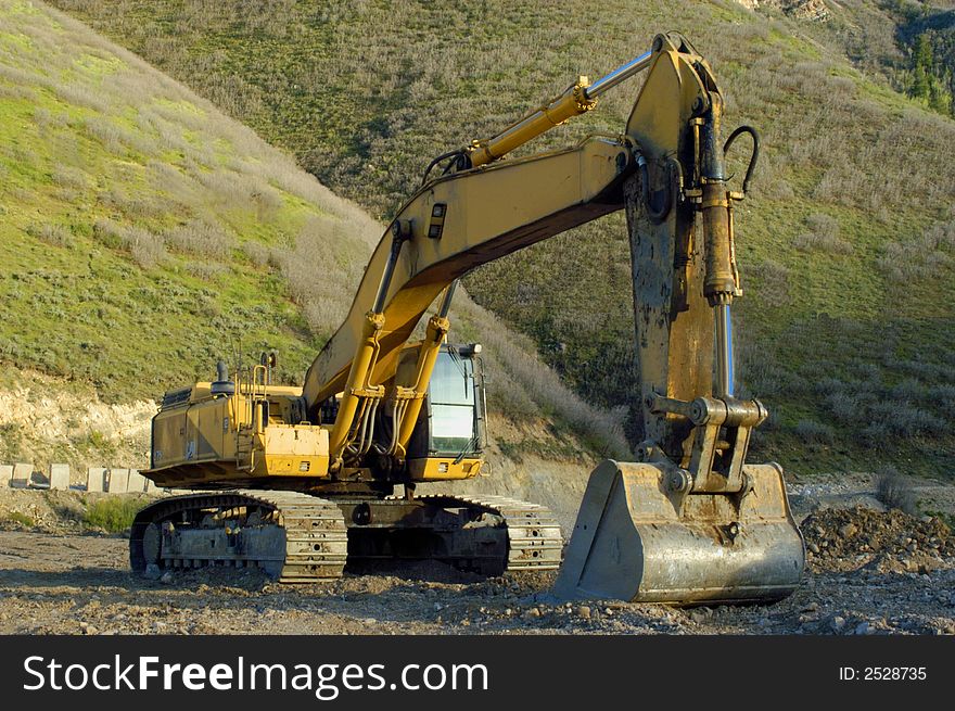 Track-hoe at construction site, mountainside behind. Track-hoe at construction site, mountainside behind