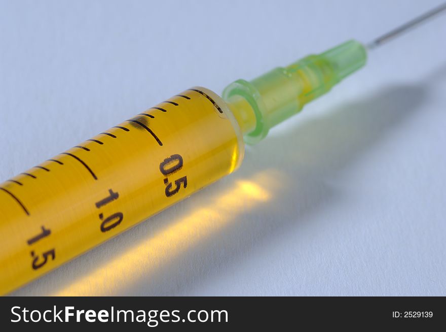 Syringe with yellow vaccine isolated. Syringe with yellow vaccine isolated