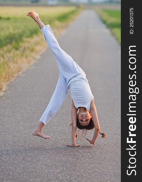 Young girl makes a cartwheel on a path