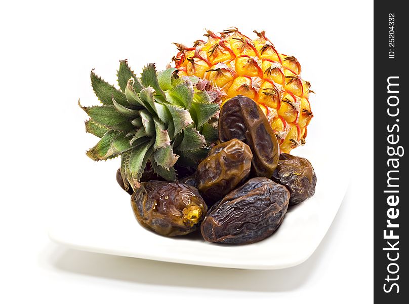 Ripe pineapple and dates on the white