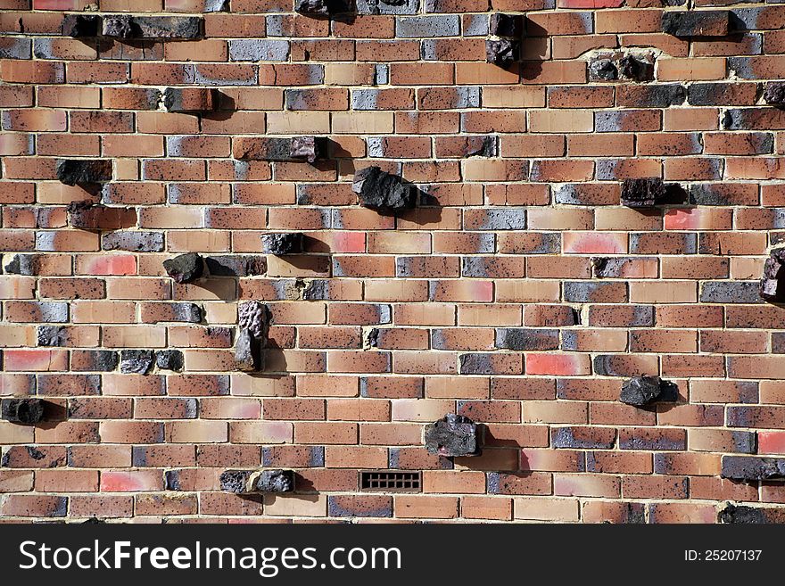 Pieces of rock have been inserted with the clay bricks to create a modern brick wall of cream, brown, red, and grey colouring with character and texture. Pieces of rock have been inserted with the clay bricks to create a modern brick wall of cream, brown, red, and grey colouring with character and texture.