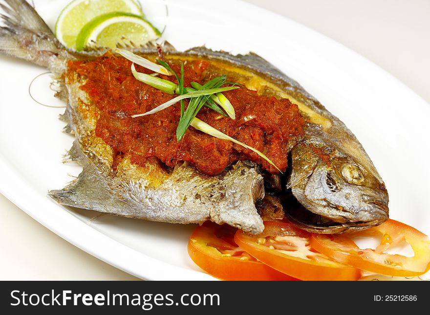 Close up of fried fish with slice lime and tomato