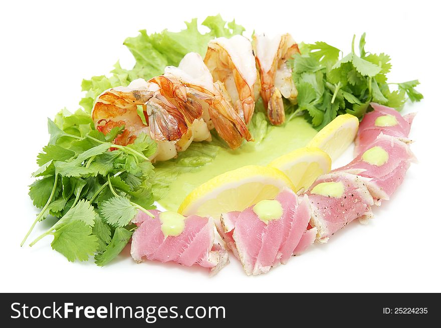 Shrimp and tuna with greens and sauce on a white background