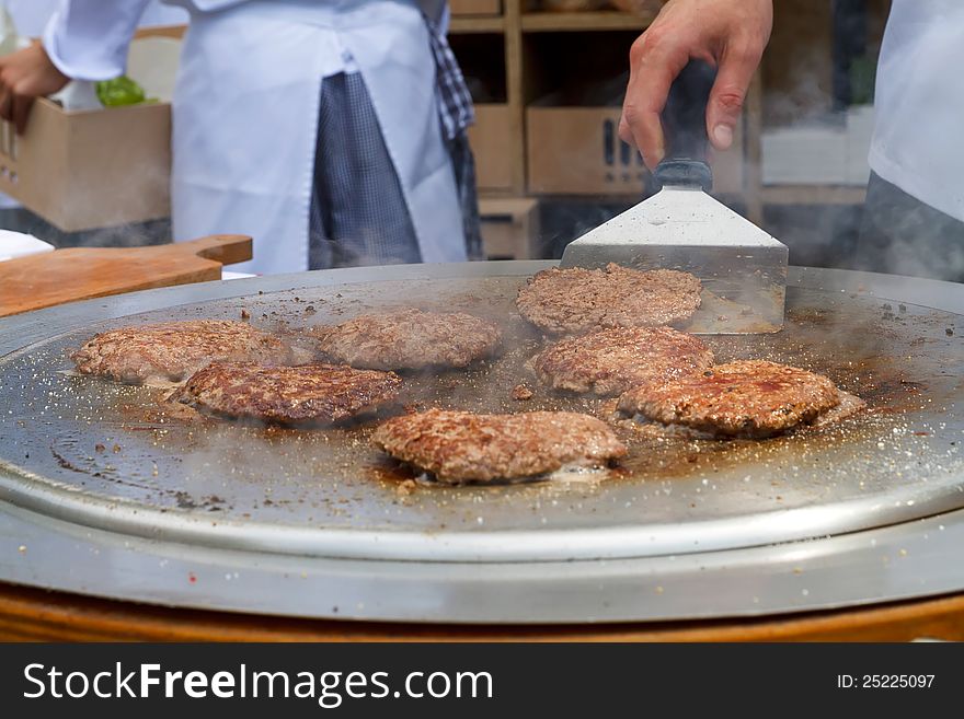 Burgers being grilled on metalic grill plate