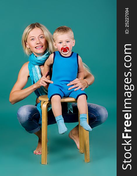 Portrait of blonde mom in jeans and a scarf and a son in a blue suit, a green background. Portrait of blonde mom in jeans and a scarf and a son in a blue suit, a green background