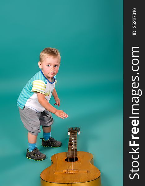 The boy reaches for the guitar, on a green background