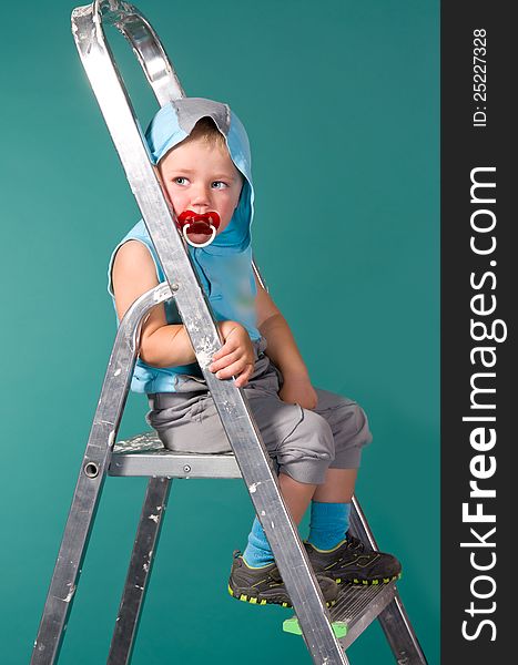 Boy sits on a ladder, in the hood