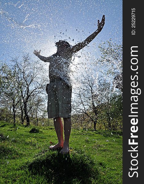 A young man enjoys the water splash in the outdoors