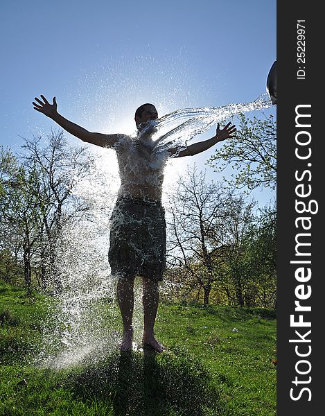 A young man enjoys the water splash in the outdoors. A young man enjoys the water splash in the outdoors