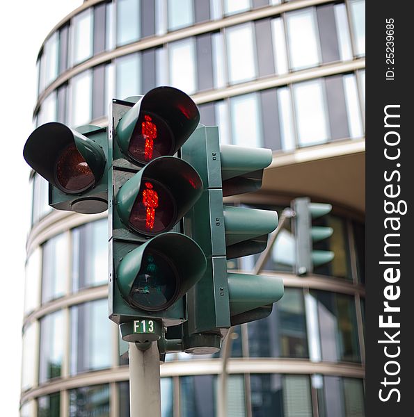 You see traffic lights in Hamburg in front of a modern office building.