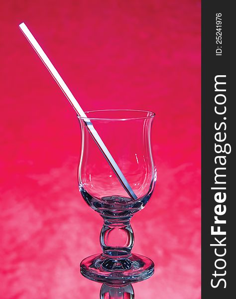 Abstract empty glass with a straw on a red background