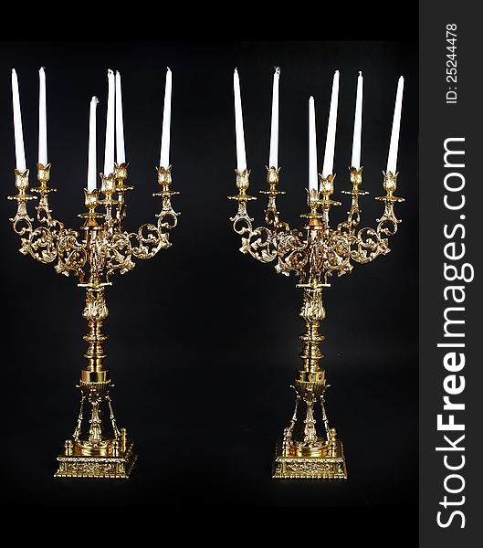 Two huge golden candleholder with white candles. Two huge golden candleholder with white candles.