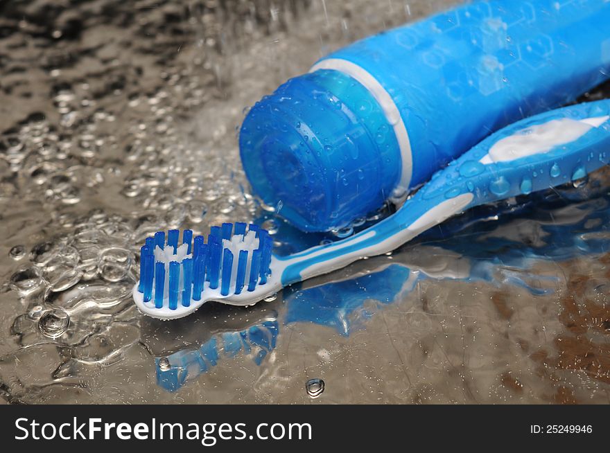 Blue toothbrush and toothpaste in running water