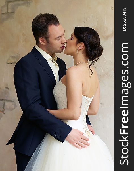 Groom kisses bride in stylish empty room. Groom kisses bride in stylish empty room