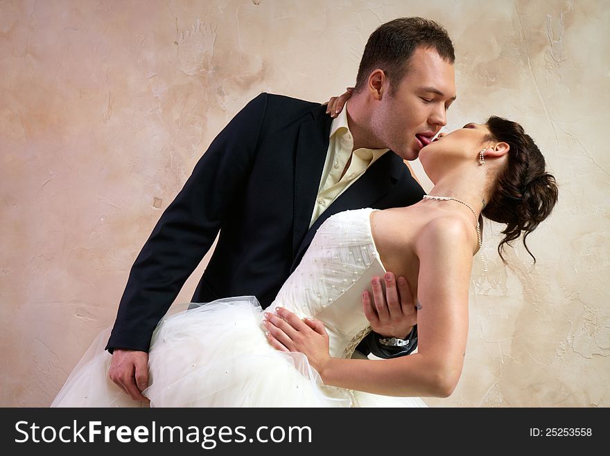 Groom kisses bride in stylish empty room. Groom kisses bride in stylish empty room