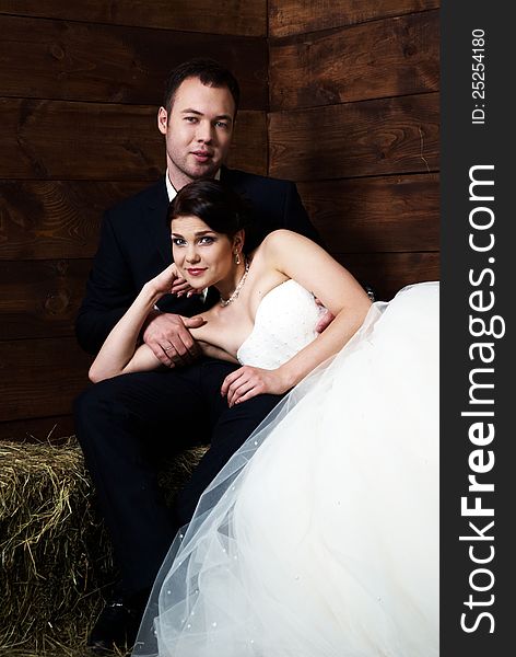 Bride lying on groom's lap in barn with hay. Bride lying on groom's lap in barn with hay