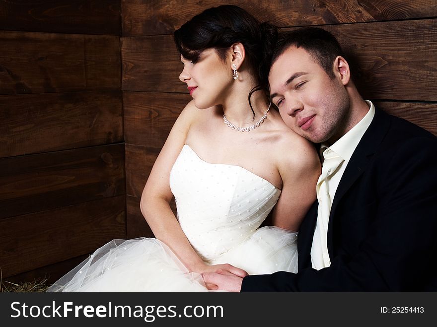 Couple in their wedding clothes sitting in hugs in barn with hay fooling with each other. Couple in their wedding clothes sitting in hugs in barn with hay fooling with each other