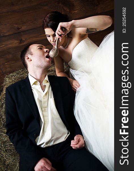 Couple in their wedding clothes in barn with hay