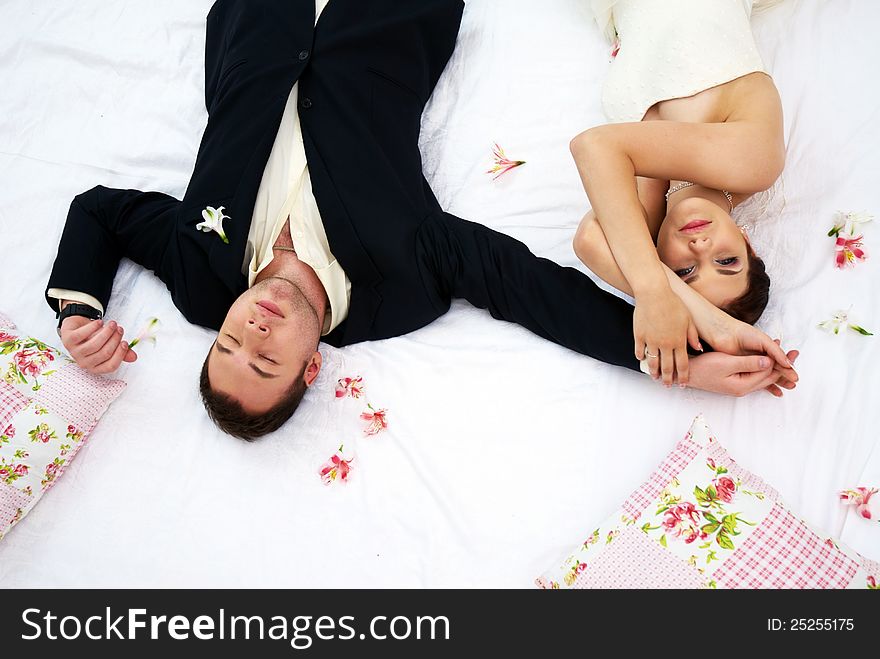 Bride and groom lying in bedroom with orchids