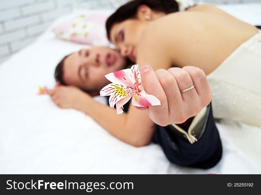 Bride and groom lying in stylish bedroom. orchid close up. Bride and groom lying in stylish bedroom. orchid close up