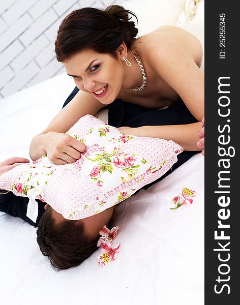 Bride And Groom Fooling In Bedroom With Orchids