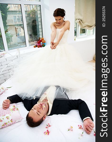 Bride And Groom Fooling In Bedroom With Orchids